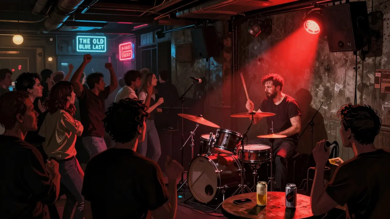 Salle de musique underground à Shoreditch avec batteur en plein jeu et foule dansante sous un éclairage rouge.
